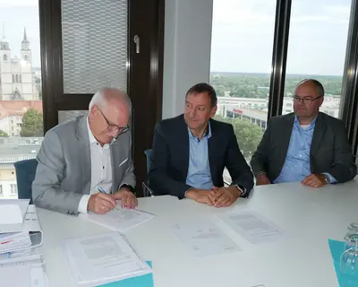 Zwei Herren von SWM und ein Herr von Avacon unterzeichnen einen Vertrag