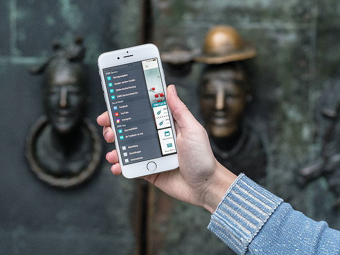 Menü in der SWM App Frau hält Handy in der Hand, auf dem das Menü der SWM App zu sehen ist