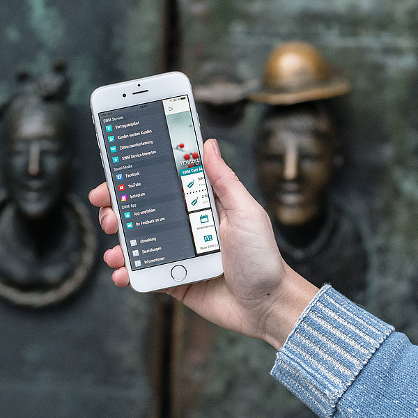 Frau hält Handy in der Hand, auf dem das Menü der SWM App zu sehen ist