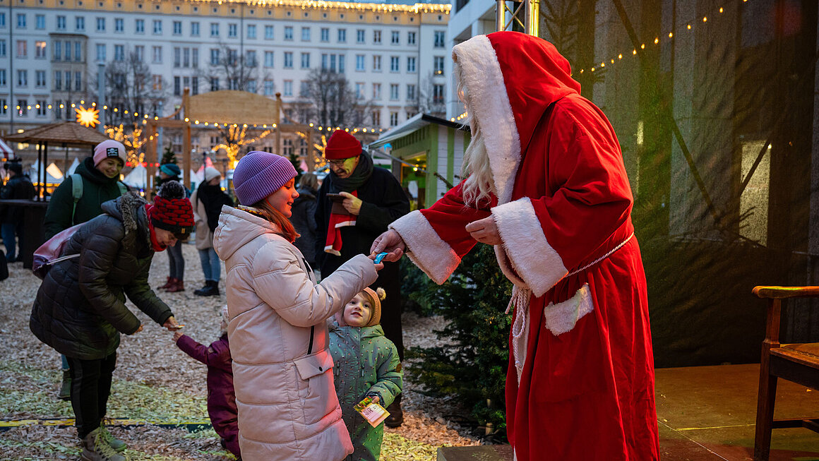 Weihnachtsmann übergibt Geschenk an ein Kind