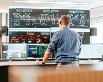 Ein Dispatcher steht vor den Bildschirmen der SWM Netzleitstelle Strom.