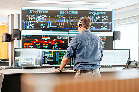 Ein Dispatcher steht vor den Bildschirmen der SWM Netzleitstelle Strom.