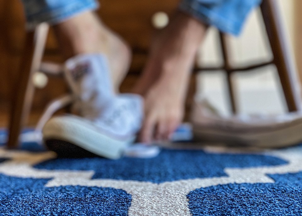 Jemand zieht seine Schuhe aus und ist dann barfuß auf dem Teppich Barfuß laufen