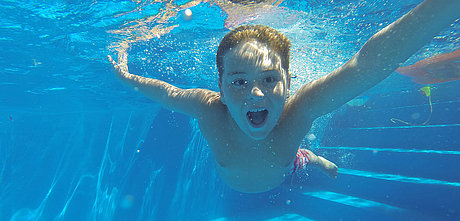 Junge schwimmt im Freibad