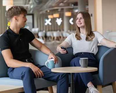 kaufmännische Auszubildende und Dualer Student sitzen in Kantine trinken in der Pause einen Kaffee zusammen