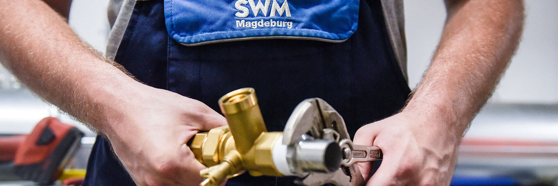 Detailfoto von SWM Azubi zum Anlagenmechaniker mit Rohr und Zange in der Hand