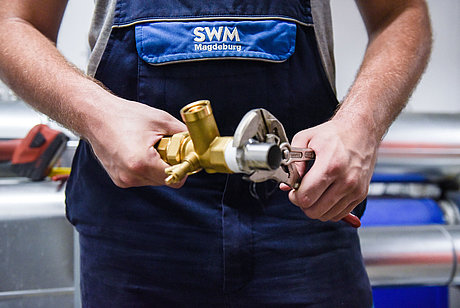 SWM Azubi Anlagenmechaniker Rohrarbeiten Detailfoto von SWM Azubi zum Anlagenmechaniker mit Rohr und Zange in der Hand
