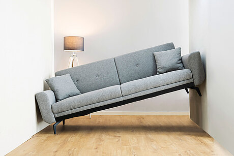 Graues Sofa passt nicht in eine Nische und steht schief