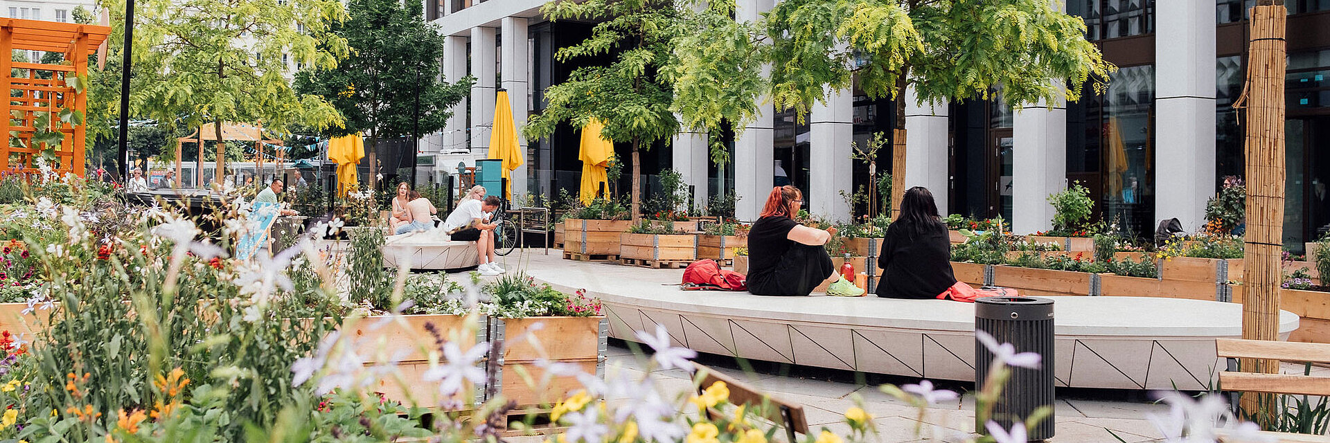 Blick in Nachbars Garten; zwei Frauen sitzen auf einer Bank