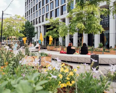 Blick in Nachbars Garten; zwei Frauen sitzen auf einer Bank