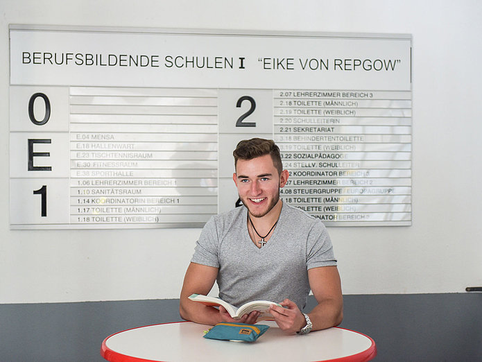 SWM Azubi Industriekaufleute in der Berufsschule SWM Azubi Industriekaufleute in der Berufsschule mit Buch in der Hand am Stehtisch