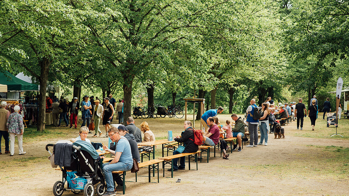 Blick auf die Grüne Messe, Besucher sitzen auf Bänken und essen