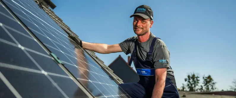 SWM Mitarbeiter montiert PV Anlage auf Kundendach