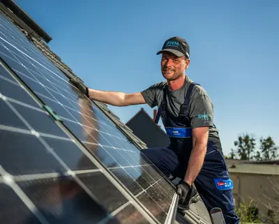 SWM Mitarbeiter montiert PV Anlage auf Kundendach