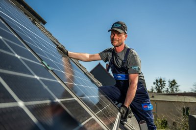 SWM Mitarbeiter montiert PV Anlage auf Kundendach