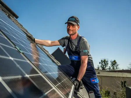 SWM Mitarbeiter montiert PV Anlage auf Kundendach