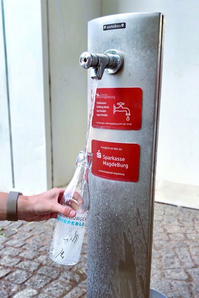 Wasserflasche wird an Trinkwasserspender gefüllt