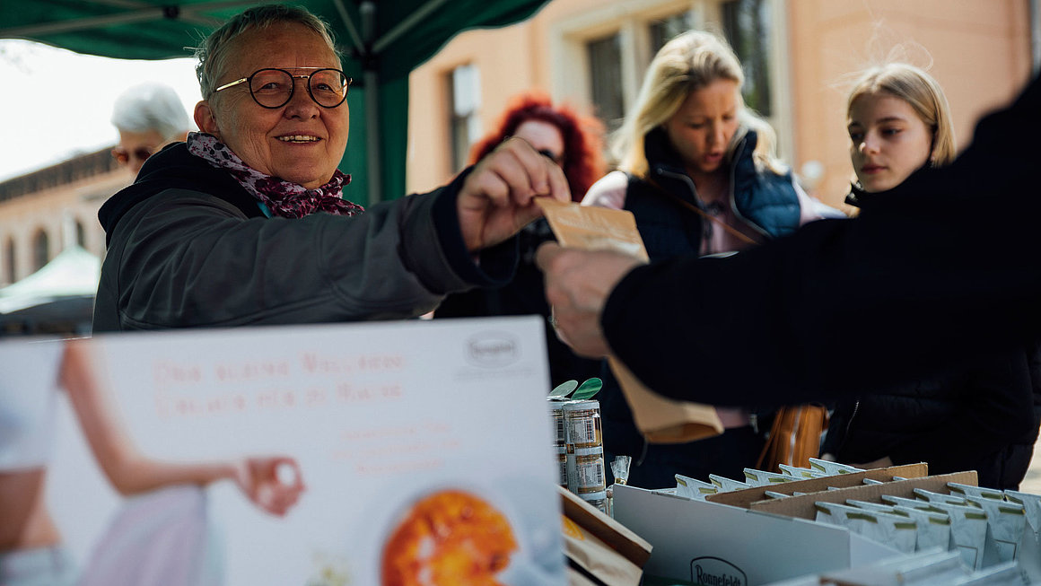 Kundin kauft etwas am Stand von Tee hoch n
