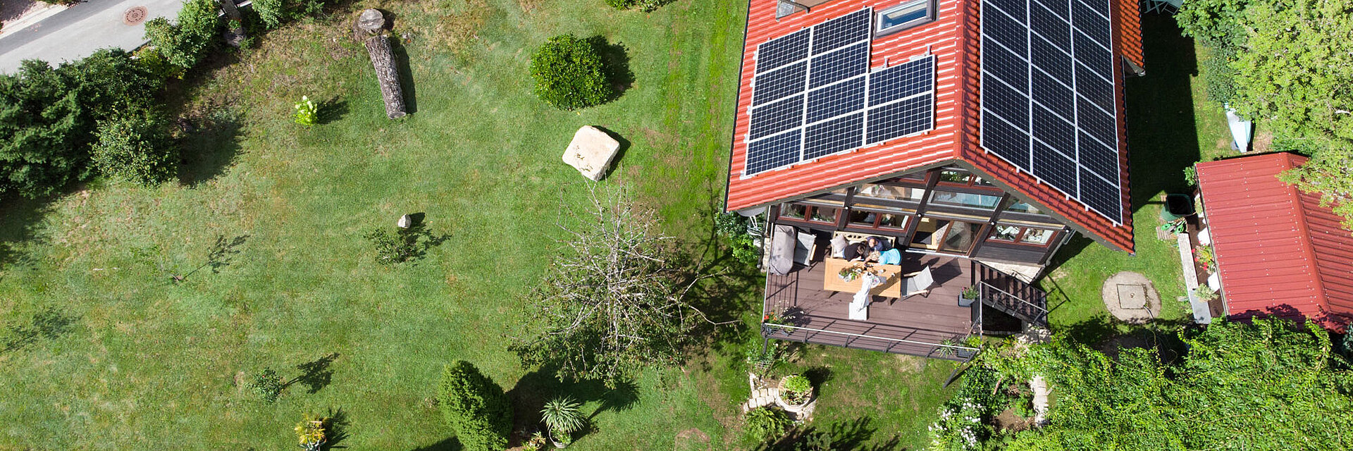 Blick von oben auf ein Wohnhaus mit Photovoltaik-Anlage auf dem Dach