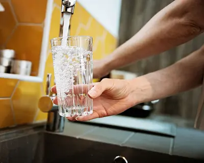 Trinkglas wird an Wasserhahn befüllt