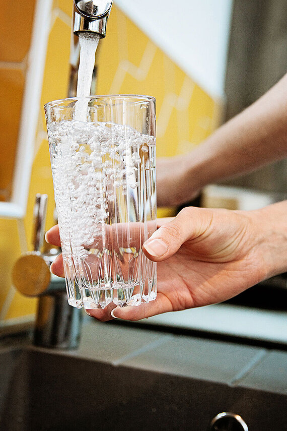 Trinkglas wird an Wasserhahn befüllt