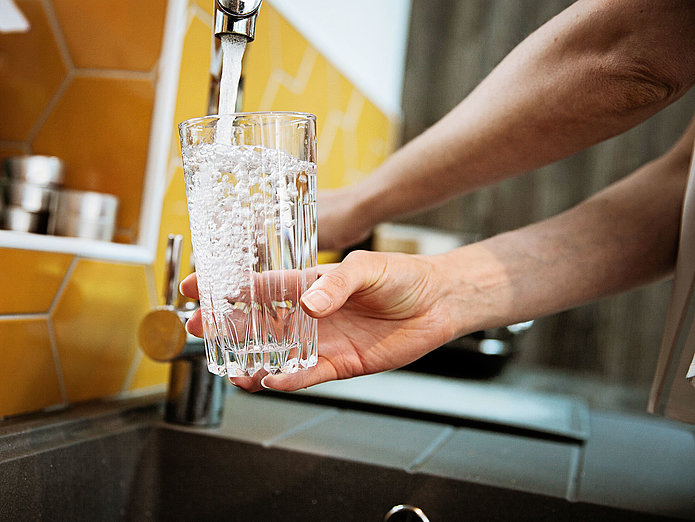 Trinkglas wird an Wasserhahn befüllt