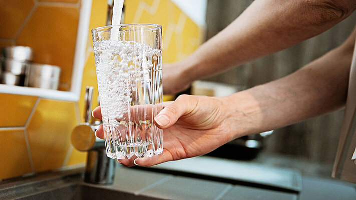 Trinkglas wird an Wasserhahn befüllt