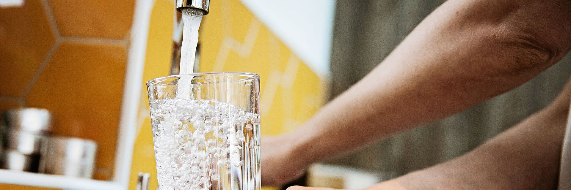 Trinkglas wird an Wasserhahn befüllt