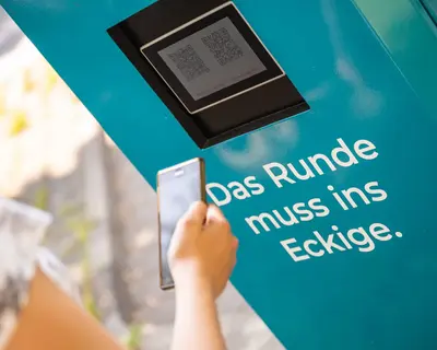 Frau scannt den QR-Code an der Ladesäule